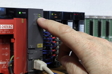 Wall Mural - plc - programmable logic controller. the hand points to the indicator led of the running diode. prod