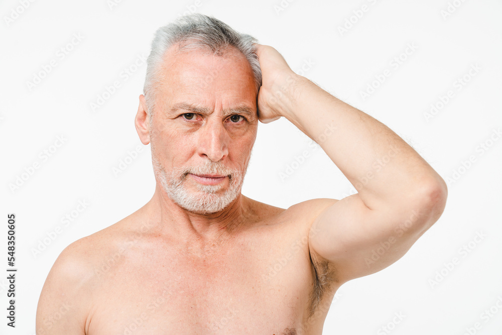 Handsome caucasian mature middle-aged senior naked man with grey hair and beard showing muscles