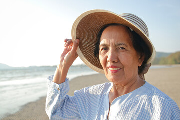 Wall Mural - Asian elderly woman Smile, happy to come to the sea. Retirement tourism. Health insurance. Elderly society in retirement age.