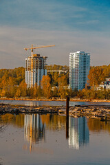 Wall Mural - Construction of a new residential district at the riverbank in  Vancouver City. The river bank and the slope covered with forest on the background of a cloudy sky