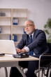 © Elnur - Old male employee in wheel-chair sitting at workplace