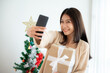 © Monster Ztudio - Young asian woman having fun taking selfie and video call talking with her friend. Female showing gift box while on video conversation with friend. Happy new year, Thanksgiving, Merry Christmas