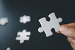 © Tinnakorn - Hand holding jigsaw puzzles, Business partnership concept. hands of businessmen connect puzzle pieces on dark background. Business concept idea, teamwork, cooperation, partnership, creative.