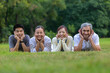 © Akarawut - Portrait of group of Asian family with father, mother, son and daughter lying down together on the grass lawn at the public park during weekend activity for recreation and wellbeing concept
