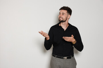 Wall Mural - Handsome man in black shirt on light grey background, space for text