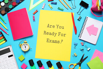 Wall Mural - Yellow paper with question Are you ready for exams and stationery on light blue table, flat lay