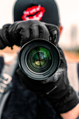 Close up of photographer holding camera with focus on lens with blurry background in center of frame
