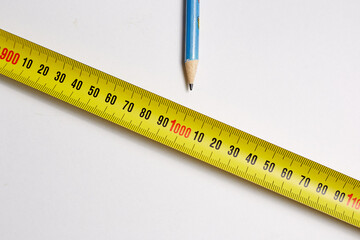 Measuring tape with a pencil on a white background is needed for construction work