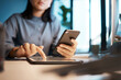 © Rene L/peopleimages.com - Night, woman hands and smartphone, tablet and planning in dark office desk, startup or company. Closeup businesswoman with phone, digital app and cloud computing, working late with website connection