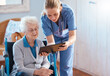 © David L/peopleimages.com - Nursing home, woman or doctor with tablet checking medical results, chart online or social media. Healthcare, tech and nurse caregiver help consulting with elderly patient in living room or bedroom
