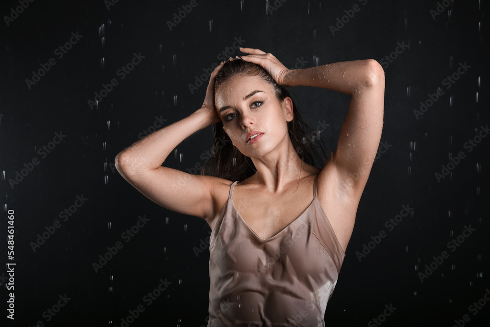 Attractive young woman and dripping water on black background