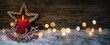 Leinwandbild Motiv Christmas candle in winter snow landscape with magic lights. Xmas Panorama, Banner. First Advent Sunday. Wood background with copy space.
