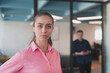 © .shock - Portrait of young smiling business woman in creative open space coworking startup office. Successful businesswoman standing in office with copyspace. Coworkers working in background.