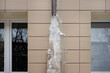 Frozen rain pipe on an apartment building. Ice on the building wall.