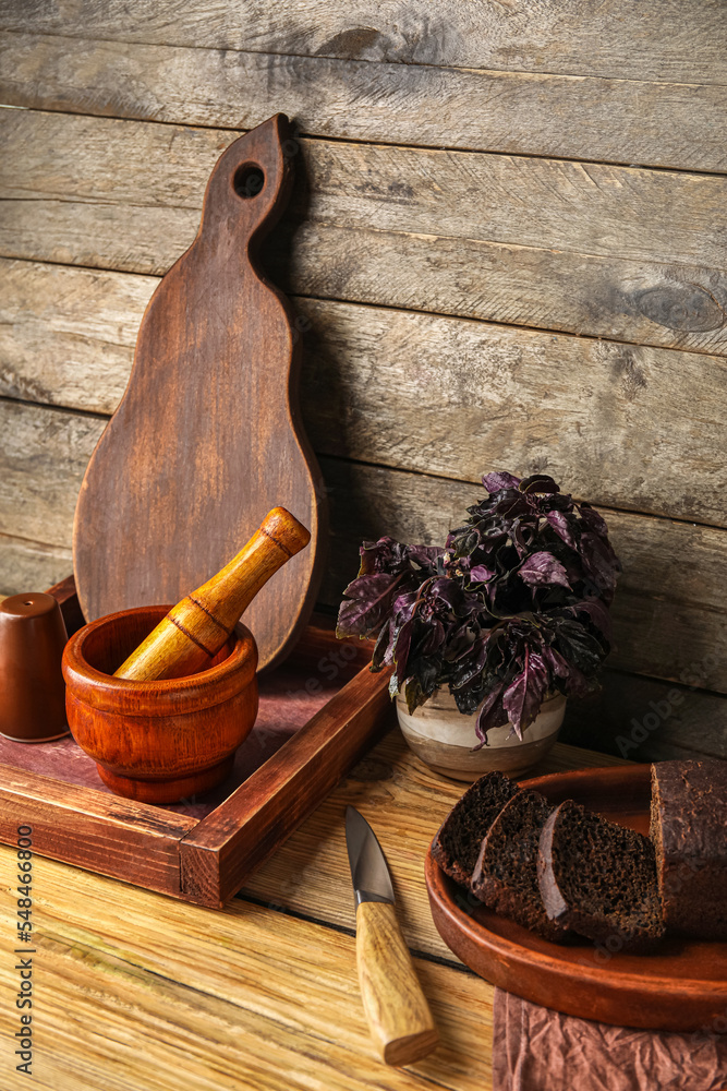 Kitchen utensils with bread and basil on dark wooden background