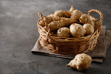 Raw Jerusalem Artichoke Root, Sunchokes In Wicker Basket And On Brown Table. Close Up.