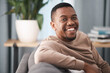 © T Hover/peopleimages.com - Face, smile and portrait of a black man relax in a living room at a house on a holiday, break or weekend. Happiness, calm and young male sitting alone in a lounge in home or apartment relaxing