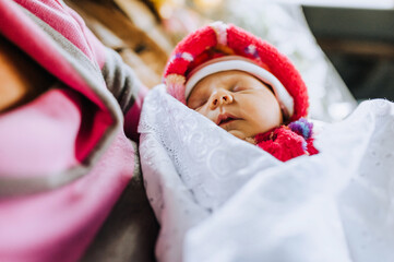 Wall Mural - A small beautiful newborn baby, a girl lies, sleeps in her mother's arms in the maternity hospital. Photography, portrait.