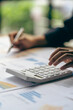 © ArLawKa - vertical view businessman hand holding a pen using a calculator Work with charts and analyze business strategies. financial statistics