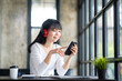 © crizzystudio - Young adult happy smiling Asian student wearing headphones talking in online chat meetings using a laptop on a university campus or at a virtual office. College female students learning remotely.