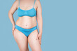 Fat woman in underwear on blue background, overweight female body with copy space
