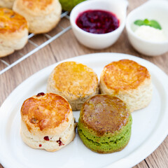 Wall Mural - Four flavours of homemade scone with raspberry jam and clotted cream (butter, cranberry, matcha and Earl Grey)