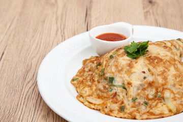 Wall Mural - Thai style omelette with minced pork, 
coriander and onion served with chilli sauce or Sriracha sauce