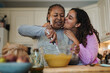 © Sabrina - Happy african daughter kissing her mother while baking together inside kitchen at home