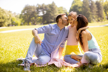 Wall Mural - Happy young family with cute little daughter having fun in the park on a sunny day