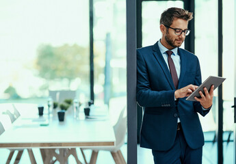 Wall Mural - Controlling his business with just a tap. Shot of a young businessman using a digital tablet in an office.