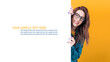 © Alen-D - Happy young women holding white board, wearing blue leather jacket, isolated on yellow background. Beautiful girl showing blank empty paper billboard with blank space for text