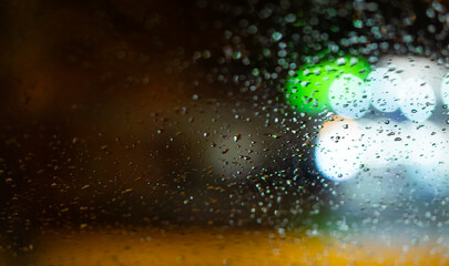 Wall Mural - Background with raindrops on window and street lighting colors