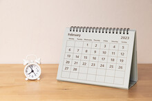 February 2023 Calendar And Small Alarm Clock On A Wooden Table
