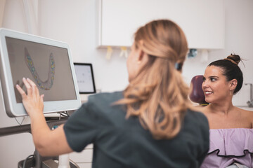 The female doctor shows the results of the digital intraoral scan of the patient's teeth in 3D on display,modern dentist.