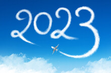Happy New Year 2023 Concept Travel On The Blue Background Below Cloudscape. Drawing By Passenger Airplane Vapor Steam Contrail In Sky.