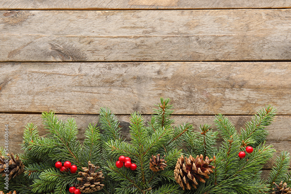 Composition with fir branches, pine cones and berries on wooden background