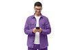 Young man in purple casual shirt looking at phone, standing
