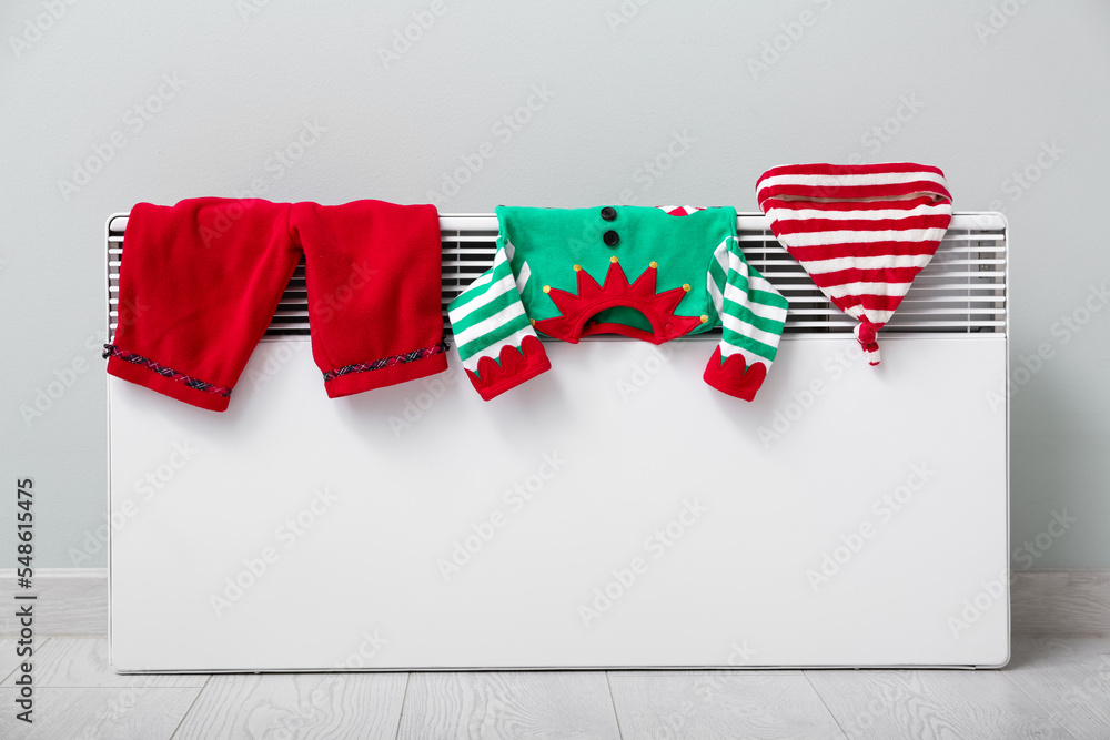 Baby elf costume drying on electric radiator near light wall