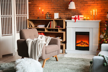 Interior of living room with fireplace, armchair and burning candles