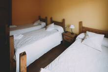 View Of A Triple Room With Three Wooden Beds In A Spanish Village Hotel.