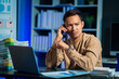 © NanSan - Overtime work concept, Handsome asian business man working late at night in office workplace. Mobile calling.
