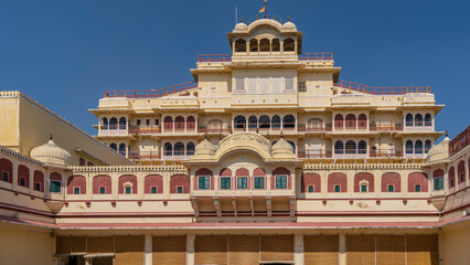 Wall Mural - An ancient palace complex in Jaipur against the blue sky. The sandstone building is decorated with arches, carvings, decorative lattices, terraces, balconies, spires. India