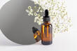 cosmetic bottle with a dropper on the background of a mirror and gypsophila. serum, essence, oil for facial skin care. natural organic cosmetics.