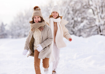 Poster - Happy active family mother and little daughter have fun in winter park, play catch-up in snowy day