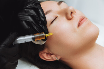 A cosmetologist performs plasmolifting on the face of a beautiful woman in a beauty salon. The concept of cosmetology.