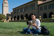 © PR Image Factory - concentrate asian korean female international student reviewing notes for test on the lawn near hoover tower during her spring semester study tour at school university in California usa