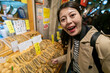© PR Image Factory - closeup of smiling asian Japanese woman tourist looking at camera and pointing at traditional preserved food at a local vendor in nishiki market in Kyoto japan
