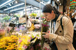 © PR Image Factory - portrait happy asian Japanese girl traveler smelling fragrant bouquet while buying flowers at a shop on teramachi street at nishiki market in Kyoto japan