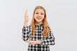 Beautiful teen girl with blonde hair wearing casual yellow t shirt, stands with his hand raised up over white studio background, smiling and gesturing hand. Education and school concept