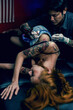 © ND STOCK - Professional tattooist makes the tattoo on a girl waist, focusing on tattoo machines in a modern studio lowlight.